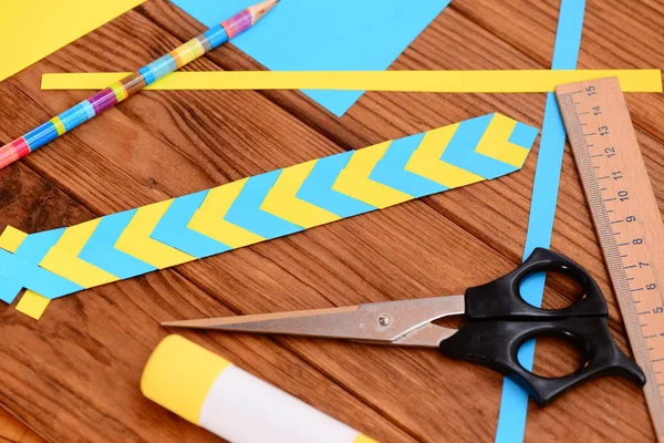 Sarı ve mavi yer işareti katlanmış kağıttan. Sopa, renkli kağıt sayfaları, cetvel, makas, yapıştırıcı bir masa üzerine kalem. Basit kağıt sanat projeleri. Kağıt katlama ile çocuklar için kağıt el sanatları