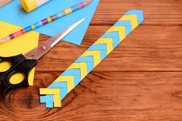 Marcador de papel para niños sobre un fondo de madera marrón con lugar vacío para el texto. Artesanía creativa de papel en casa o en la escuela. Papelería puesta en una mesa. Idea de marcadores fácil y rápida para los niños. Vista superior — Foto de Stock