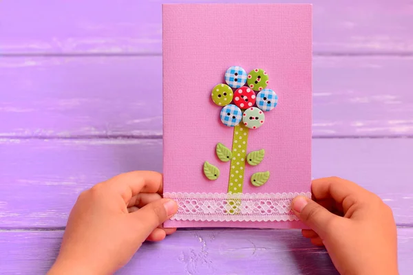Το παιδί κατέχει μια κάρτα λουλούδι στα χέρια του. Το παιδί έκανε μια ευχετήρια κάρτα για τη μαμά ή τον μπαμπά. Γενέθλια, ημέρα της μητέρας, πατέρες ημέρα δώρο ιδέα. Πώς να κάνει ευχετήρια κάρτα. Κινηματογράφηση σε πρώτο πλάνο — Φωτογραφία Αρχείου