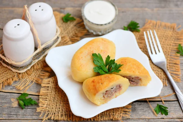 Kızarmış biftek ve patates zrazy bir servis tabağı üzerinde zemin. Çatal, ekşi krema sosu bir cam kase, tuz ve biber shaker ahşap bir masa üzerinde. Rustik tarzı. Portre