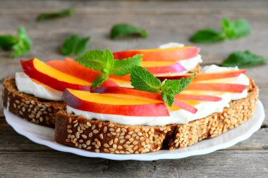 Krem peynir, taze nektarin ve nane bir servis tabağı ve vintage ahşap bir masa ile basit sandviç. Kadınların ağırlık kaybı için diyet. Portre