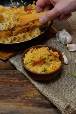 Geleneksel baharatlı yemek pilav, salatalık turşusu ile kase, ahşap arka plan ve çuval bezi ekmek dilimleri ile Vintage kil kase. Rustik tarzı 