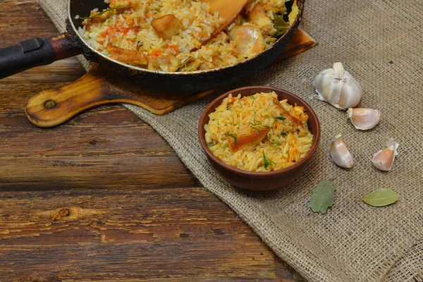 Geleneksel baharatlı yemek pilav, salatalık turşusu ile kase, ahşap arka plan ve çuval bezi ekmek dilimleri ile Vintage kil kase. Rustik tarzı 