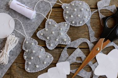 İle yapmak için bir şeyler için Noel gibi. Gri çam ağacı, top ve beyaz boncuk ile yıldız süs eşyaları hissettim. Makas, iğne, iplik kağıt kalıpları, kordon vintage ahşap bir masa üzerinde. Üstten Görünüm