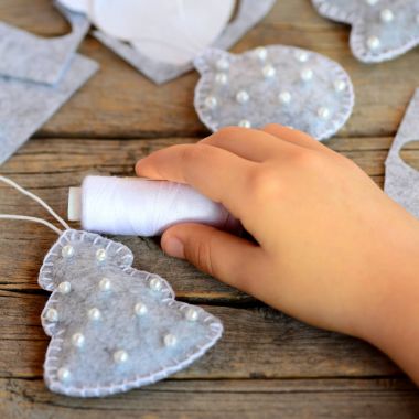Çocuk Noel süsleri yapmak. Top ve köknar ağacı keçe ahşap bir masa üzerinde yapılmış. Hızlı Noel dikiş desenleri ve fikirler. Arkadaşlar için dikmek için el yapımı hediyeler