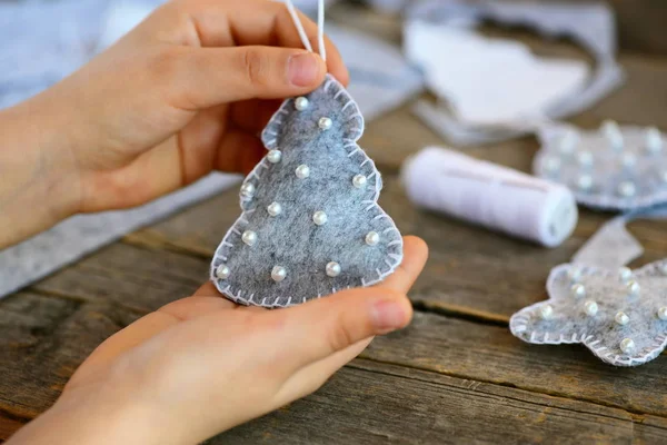 Küçük çocuk bir Noel oyuncak gösterir. Çocuk Noel oyuncak elinde tutar. Çocuk bir Noel ağacı süsleme keçe üzerinden dikilmektedir. Kış sanat projesi çocuklar tüm yaş için