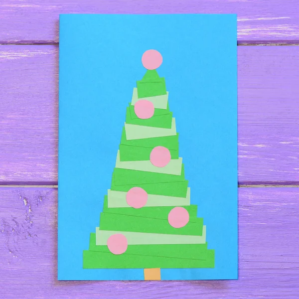 Christmas card isolated on purple wooden background. Greeting card with a Christmas tree. Easy paper crafts for children. Closeup