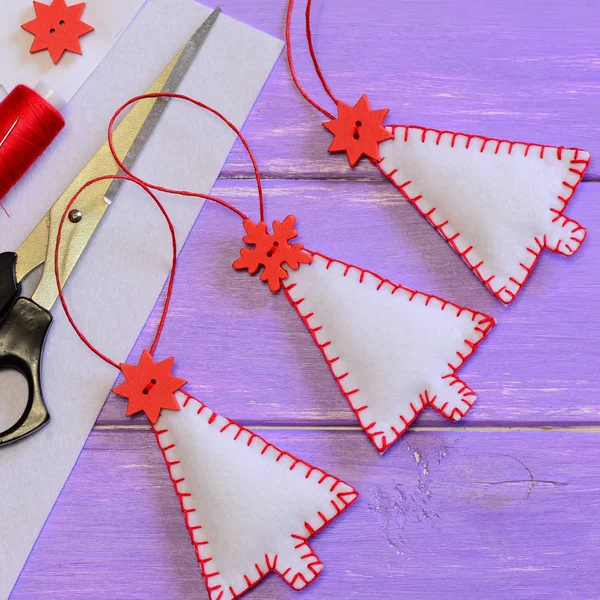 Decoraciones del árbol de Navidad, materiales artesanales y herramientas sobre un fondo de madera púrpura. Artesanías simples hechas de fieltro. Idea de coser a mano. Pared de Navidad y decoración colgante. Vista superior. Primer plano. —  Fotos de Stock