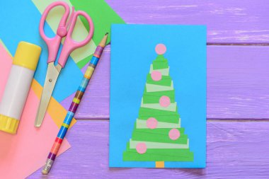 Kolay ev yapımı Noel kartı, makas, yapıştırıcı, kalem, mor ahşap masa renkli kağıda. Bir Noel ağacı ile güzel tebrik kartı. Kağıttan tebrik kartları yapmak için yaratıcı bir fikir. Üstten Görünüm