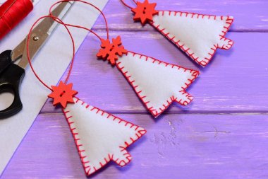 Dekorasyon, el sanatları malzemeleri ve araçları mor bir ahşap masa üzerinde Noel ağaçları. El yapımı keçe el sanatları. Dikiş ev yapımı Noel hediyeleri. Noel duvar ve süslemeleri asılı. Portre