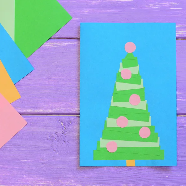 Buon Natale, fogli di carta colorati su tavolo di legno viola. Design creativo e semplice del biglietto di auguri di carta. Facile fai da te idea di artigianato biglietto di Natale per i bambini. Vista dall'alto — Foto Stock