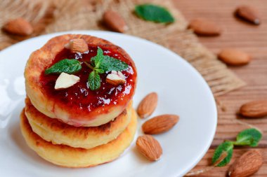 Süzme peynir krep. Kızarmış peynir berry reçel ve badem beyaz tabakta krep. Geleneksel Rus syrniki tarifi