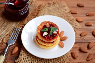 Küçük syrniki. Berry reçel ve beyaz tabakta badem Fried lor krep. Rus krep tarifi. Sağlıklı kahvaltı fikir 