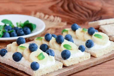 Süzme peynir, muz ve çilek ahşap tahta üzerinde ev crispbread tost. Süzme peynir fotoğraf ile sağlıklı sandviç. Portre