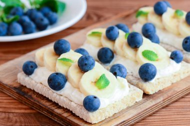 Süzme peynir, muz ve çilek sandviç. Crispbread ahşap tahta üzerinde sandviçle diyet. Portre