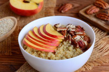 Quinoa yulaf lapası meyve ve fındık ile. Taze elma ve pecans beyaz bir kase ile sağlıklı quinoa yulaf lapası. Rustik tarzı. Portre