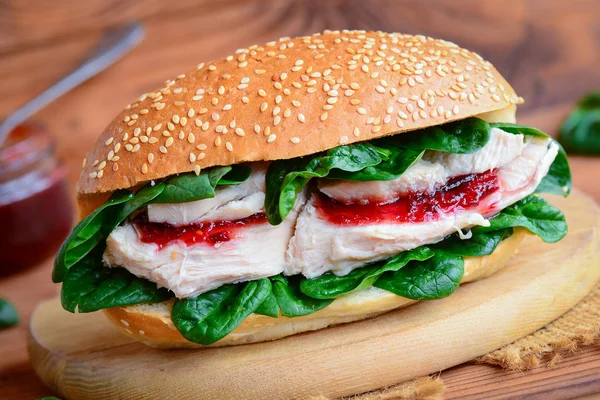 Healthy chicken breast burger recipe. Home chicken burger with spinach and berry jam on a wooden board. Closeup