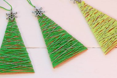Ahşap bir masa üzerinde Noel ağaçları. Yaratıcı Noel ağaçları eski karton kutu ve pamuk ipliği yaptı. Geri dönüşümlü el sanatları. Ev yapımı kış el sanatları fikir çocuklar için. Portre. Kolay geri dönüşümlü el sanatları. Okul için geri dönüşüm projeleri