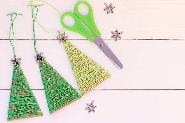 Christmas trees decor on a wooden background with copy space. Homemade Christmas trees decor from old cardboard box and cotton yarn. Easy crafts made with recycled materials. Top view. Easy recycled crafts. Recycling projects for school