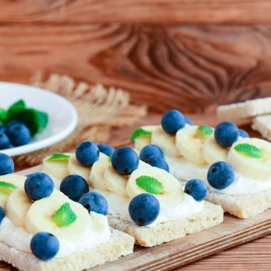 Ev yapımı peynir sandviç krema, muz ve çilek. Ahşap tahta üzerinde Topingler ile düşük kalorili kraker ekmek. Portre. Sağlıklı crispbread Tepesi. Kraker diyet. Kraker Tepesi. Kilo kaybı için sağlıklı kraker. Sağlıklı kraker tarifi