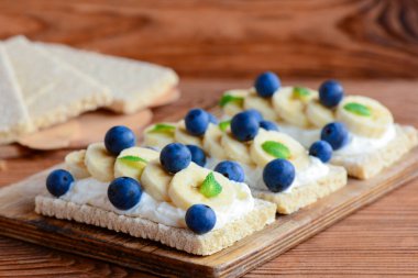 Süzme peynir, muz ve çilek ahşap tahta üzerinde Crispbreads. Süzme peynir açık sandviç fotoğraf. Portre