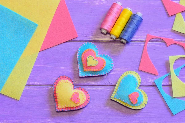 Valentines day decorations idea. Beautiful felt heart decorations, thread set, felt sheets and pieces on wooden table. Creative Valentines gift idea. Easy sewing Valentines day gifts. Top view. Romantic decorating idea. Homemade Valentine decorations
