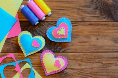 Sevgililer günü kalp süsler. Yaratıcı kalp süsler, ahşap bir masa üzerine koymak, keçe yaprak iş parçacığı. Çocuklar için hızlı ve kolay dikiş projeler. Sevgililer günü ev yapımı el sanatları. Üstten Görünüm. Kolay dikiş hobi. Dikiş projeler yeni başlayanlar için