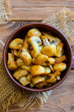 Fried mantar. Kızarmış bir ahşap zemin üzerine bir kase mantar dilimleri. Kolay mantar tarifi. Dikey fotoğraf. Portre. Üstten Görünüm. Akşam yemeği için kolay mantar tarifi. Mantar tarifi sağlıklı