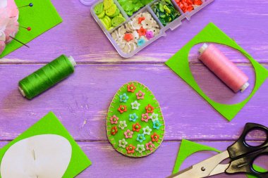 Paskalya yumurtası dekorasyon çiçek desenli. Yumurta, makas, kağıt şablonu, iş parçacığı, beades mor ahşap masa üzerinde kutusuyla hissettim. Paskalya için kolay DIY fikir. Paskalya yortusu yumurta dekor. Paskalya için kolay DIY fikir. Paskalya el sanatları yapmak. DIY Paskalya dekorasyon