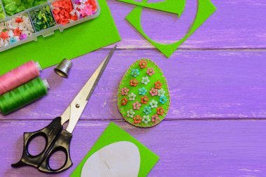 Paskalya yortusu yumurta dekor çiçek desenli. Yumurta dekor, makas, kağıt şablonu, iş parçacığı, yüksük, beades kopya alanı ile ahşap arka plan üzerinde kutusuyla hissettim. Kumaş Paskalya yortusu yumurta zanaat. Paskalya için kolay DIY fikir. Paskalya el sanatları yapmak. DIY Paskalya dekorasyon