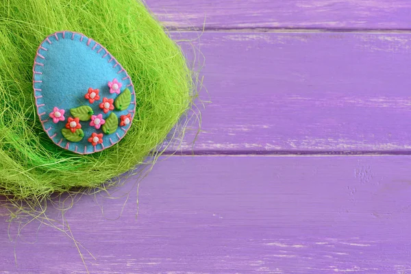 Easter egg crafts with colorful plastic beads. Felt egg ornament in the nest and on wooden background with copy space. Happy Easter greeting card. Idea for Easter decor crafts. Small sewing projects for beginners. Hand sewing projects
