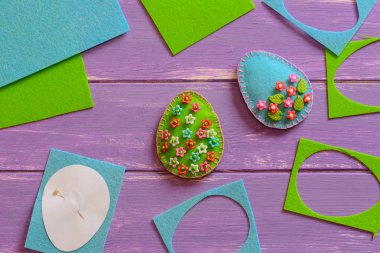 Mavi ve yeşil Paskalya yumurtaları hissettim, hurda ve levhalar, kağıt şablonu mor ahşap arka plan üzerinde hissetti. Kolay Paskalya el sanatları. Paskalya DIY süslemeleri ve Paskalya için gdiy el sanatları için bir fikir. Güzel el sanatları. Yaratıcılık Paskalya yumurtaları. Paskalya öğretici hissettim