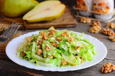 Hızlı armut ve lahana salatası. Ev yapımı salata taze armut, lahana ve ceviz beyaz bir tabak ve rustik ahşap arka plan ile. Hızlı sağlıklı salata fikir. Portre. Taze sebze salatası. Çiğ sebze salatası tarifi