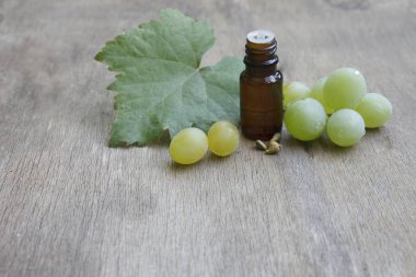 Cam kavanozda üzüm tohumu yağı ve eski ahşap masada taze üzüm. Spa, Biyoloji, Çevre Ürünleri kavramı.