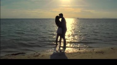 Romantik Coulpe gün batımında sahilde öpüşme