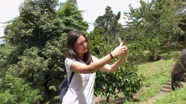 Молодая женщина делает селфи в парке со смартфоном — стоковое видео