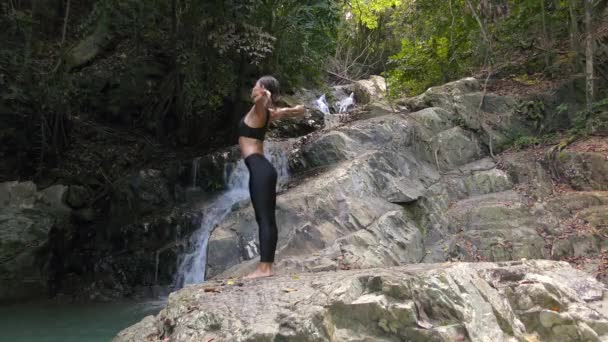Junge Frau meditiert am Wasserfall — Stockvideo