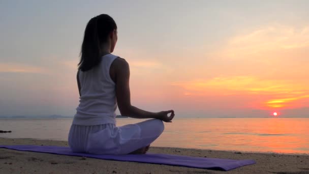 Jonge vrouw mediteert op de zonsondergang zee — Stockvideo