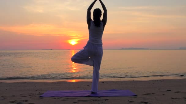 Asiatin praktiziert Yoga am Meer bei Sonnenuntergang — Stockvideo