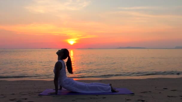 Femme asiatique pratiquant le yoga à la mer du coucher du soleil — Video