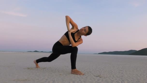 日没時にビーチでヨガを練習する女性 海で経験を積んだ女性 — ストック動画