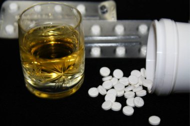Benzodiazepines or other pills and glass of alcohol, illustrative photo, dangerous of overdose, suicide, depression, drug addiction... not taken drugs and alcohol together.  clipart