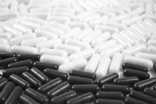Black and white medicine tablets drugs background image with dark capsules forward and light back. — Stock Photo, Image