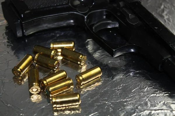 Pistol gun detail with brass golden munition on shiny silver desk