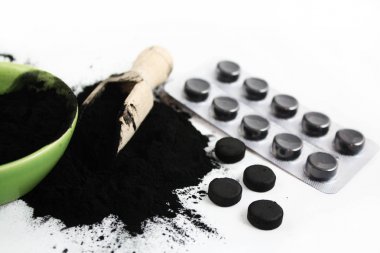 Beyaz, sağlıklı yaşam konsepti üzerine izole kömür tozu ve hapları plaka aktive