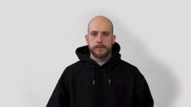   Sakallı bir adam öksürüyor ve beyaz bir arka plana tıbbi maske takıyor. Korona virüsü, koronavirüs.