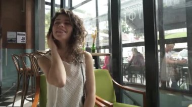  Kıvırcık saçlı kız kulaklıkla müzik dinler ve bir yaz kafesinde dans eder.