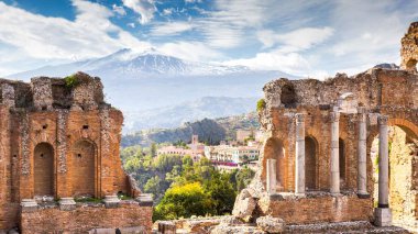 Arka planda Taormina ve Etna Dağı 'ndaki antik Yunan tiyatrosunun kalıntıları ve sütunları var. Sicilya, İtalya, Avrupa.