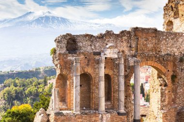 Arka planda Taormina ve Etna Dağı 'ndaki antik Yunan tiyatrosunun kalıntıları ve sütunları var. Sicilya, İtalya, Avrupa.