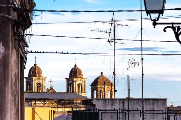 View from a roof. Cables, antennas and church's dome over blue sky. Small town Acireale in Sicily, Italy, Europe.